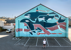 Creative Debuts artist in front of exterior mural showing swimmer and orca