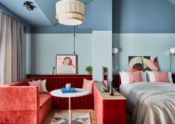 Pale blue walled room at Locke Munich with rust coloured seating area