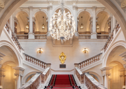Great chandelier hangs above marble staircase at The OWO, lighting by Lutron