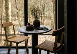 wooden table and chair in front of window looking out to woodland
