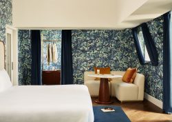 A grand suite with patterned blue walls, high ceilings, and superking bed