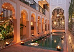 candlelight and arches around courtyard pool in IZZA Marrakech