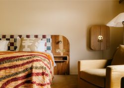 striped woven throw on bed with hand crafted cushions and wooden headboard
