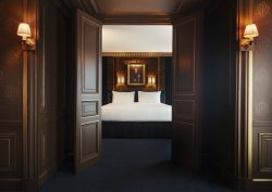 view from corridor into guestroom with portrait on the wall above the bed in Maison Proust