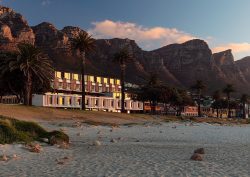 Morea House exterior with Camps Bay beach in front and mountains behind