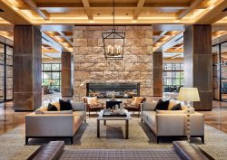 central stone fireplace with seating below ranch style wooden beams in the lobby of Omni PGA Frisco Resort