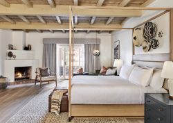rustic wooden four poster bed with baskets on the wall and a fireplace in Omni Tucson National Resort