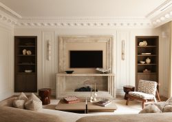 curved couch facing period fireplace in Parisian apartment decorated in neutral tones