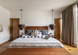 guestroom in hotel Majagua with black and white woven bedcover, and wooden surfaces next to floor to ceiling window