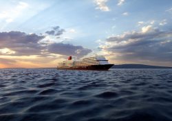 Cunard's Queen Anne in profile sailing in twilight