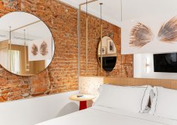 round mirror on exposed brick wall in hotel guestroom