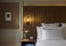 detail of bed with white linen against panelled headboard and suspended bedside light in Rosewood Amsterdam guestroom