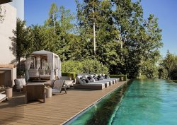 pool side loungers and a swimming pool lined by trees at Rosewood Schloss-Fuschl