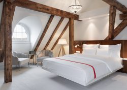 loft guestroom in Ruby Mimi Zurich with exposed wooden beams above the bed