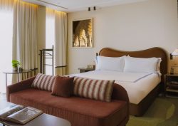 brown sofa in front of bed with curved headboard in Thompson Seville