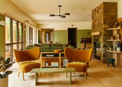 ochre chairs and olive green walls with stone fireplace in lounge of Trailborn Highlands hotel