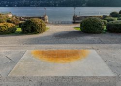 carpet with cream and orange abstract design on paving next to a lake