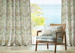 chair in william morris fabric in front of curtains and sea view