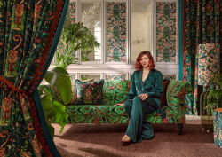 artist emma shipley on a green velvet couch with patterned drapes from Mythica collection