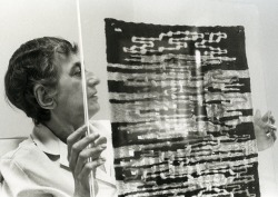Black and white image of artists Anni Albers, holding a textile piece of artwork