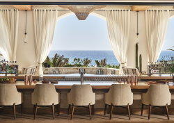 chair looking out across table and drapes to pool and sea at Four Seasons Cabo design by Meyer Davis