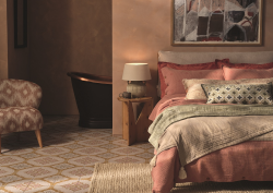 bedroom with layered textiles on bed and patterned tiles from Hyperion on the floor