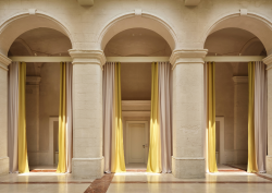 3 arches in cream stone framed with yellow floor to ceiling curtains in Vista Ostuni - a five-star luxury hotel and part of the Vista brand