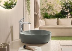 moss green rounded washbasin by villeroy & boch with water from tap and greenery in the background