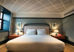 double bed in hotel guestroom with bed side lights lit up on either side