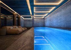 indoor spa pool at ski chalet with bright blue water contrasting with raw concrete walls