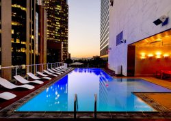hotel swimming pool with view through highrise buildings to sunset