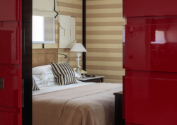 view through red doors into bedroom with striped walls in Rocco Forte House Milan