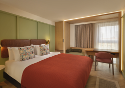 green wall and orange throw on bed in guestroom at The Reach Manchester