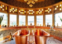 two freestanding copper baths in front of rounded windows with stained glass detail and view across denver
